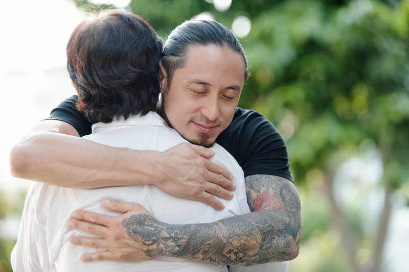 Elder son embracing his mother during their meeting outdoors