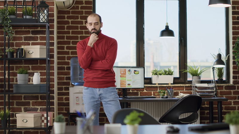 Indecisive employee walking around office and thinking about strategy to develop marketing project. Contemplative adult brainstorming ideas to work on financial analysis, pondering solution.