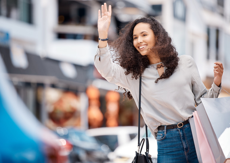 Urban woman, calling taxi and retail bags after positive shopping trip in a busy city.