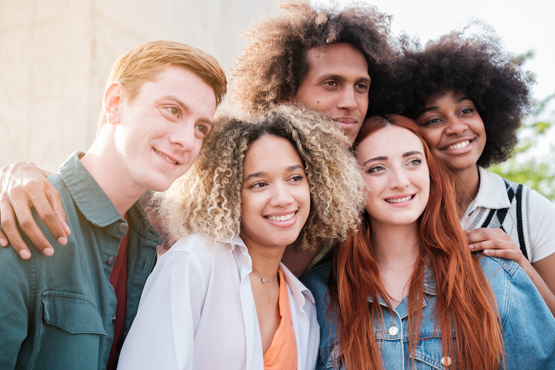 Group of young and diverse friends together laughing outdoors.