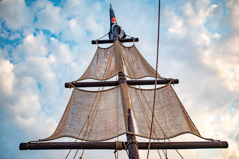 Bottom view of a ship mast with beige sails 