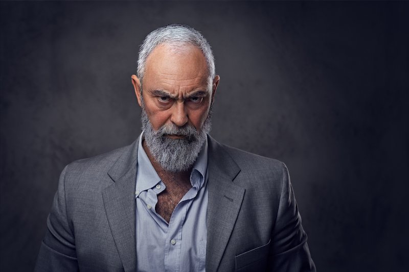 Shot of successful elderly businessman staring at camera dressed in gray suit.