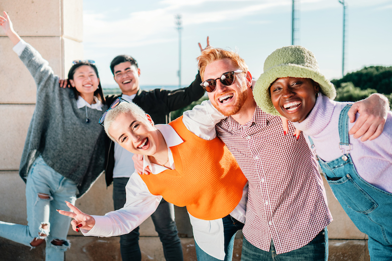 Portrait of cheerful multiracial teen friends posing at camera outdoors, smiling and laughing