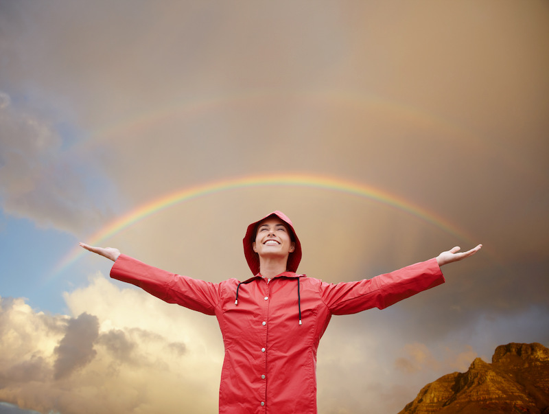 Cropped shot of an attractive young woman standing out in the elements while wearing a red raincoat and feeling positive