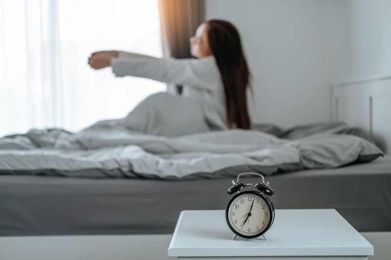 Asian woman wakes up and disturbed by alarm clock in the early morning