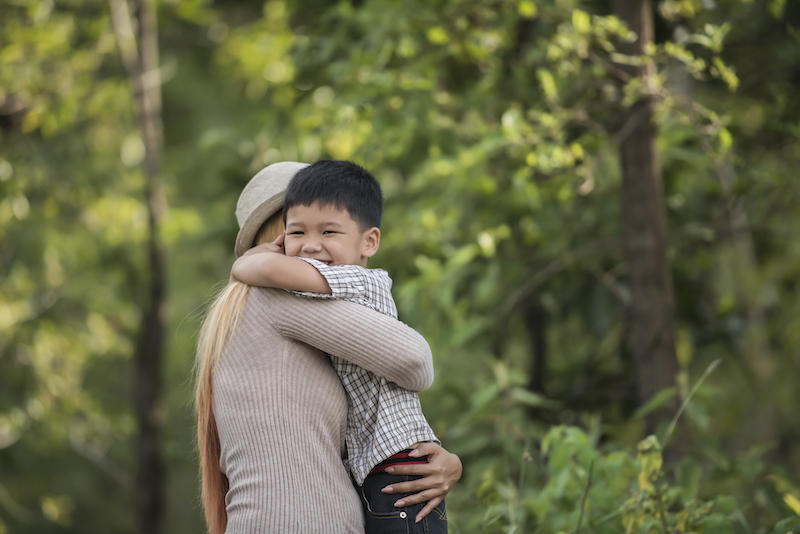 Portrait of mother and son happy cuddle together in the park.