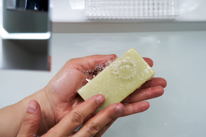 The process of washing hands with natural soap over the sink.