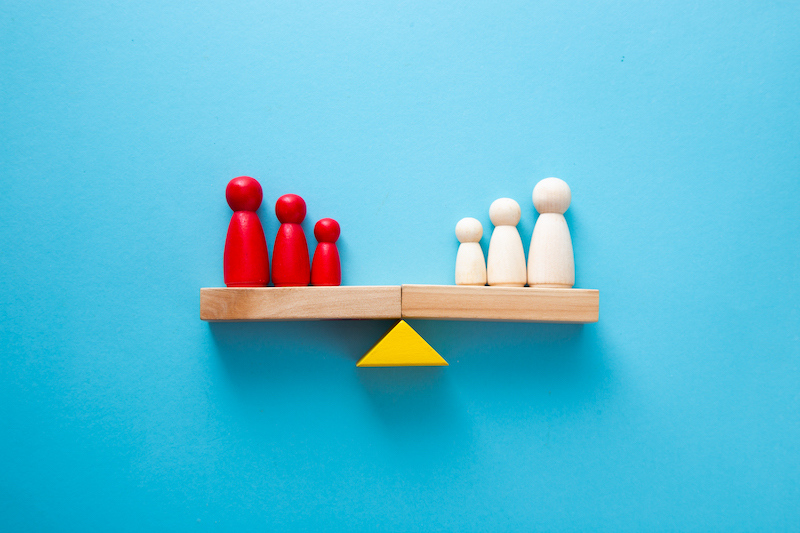 two families of peg men, one red, one white, balanced evenly on a see-saw