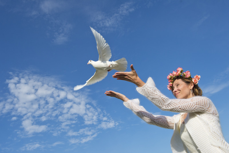 Woman releasing white dove into sky