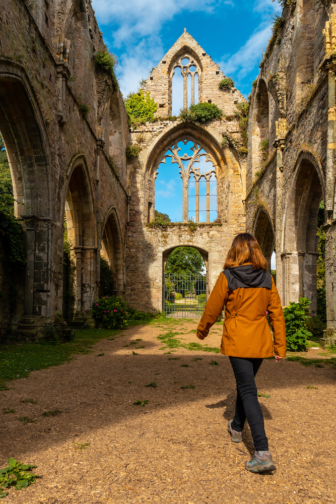 A young woman visiting the ruins of the Abbaye de Beauport church in the village of Paimpo