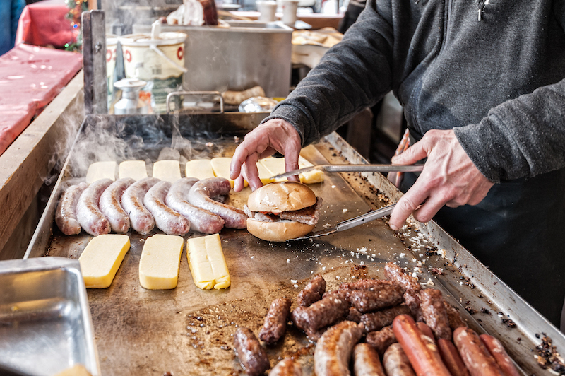 man cooking burgers and hot dogs