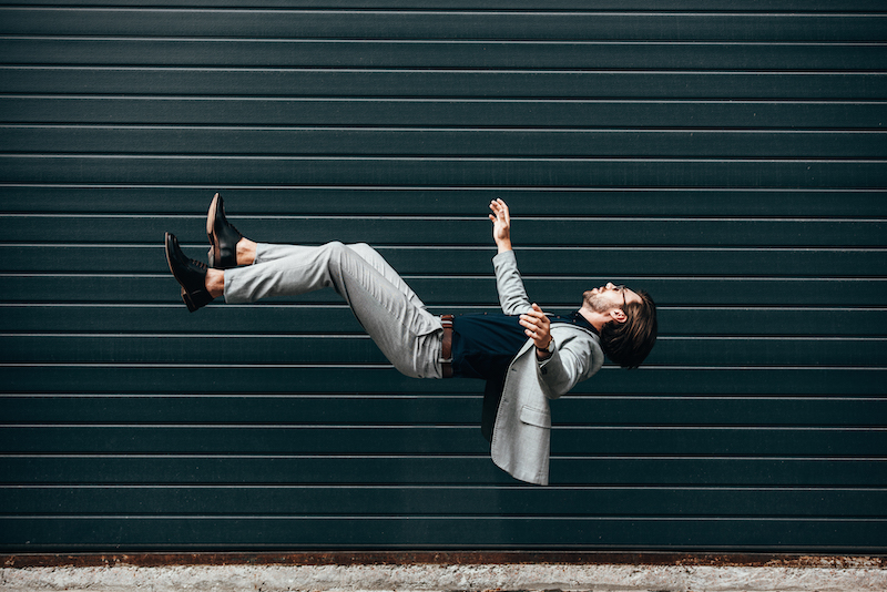 side view of handsome young businessman with briefcase falling in front of roller gate