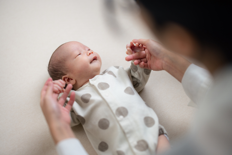 Mum helps baby to do exercise on hand