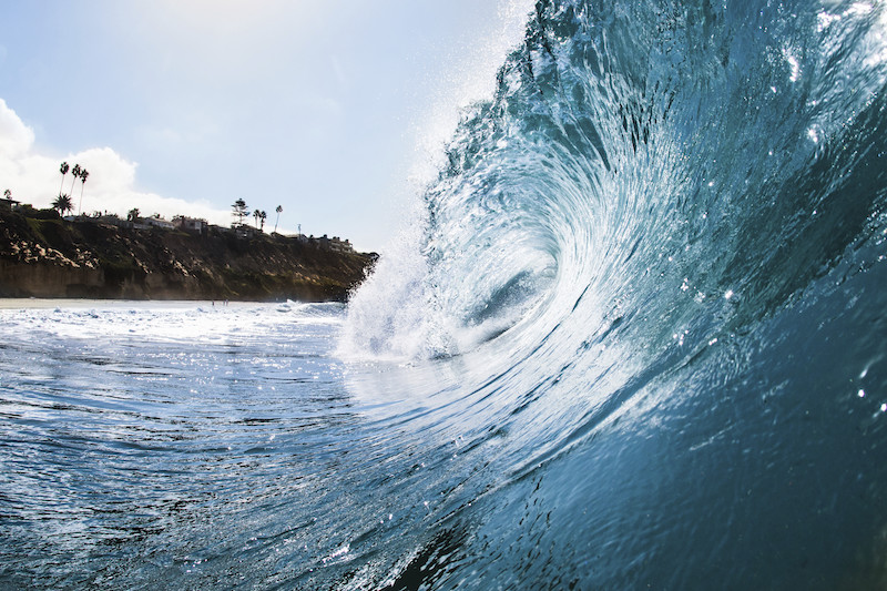 Surface level view of rolling ocean wave and coastline. Encinitas, California, USA