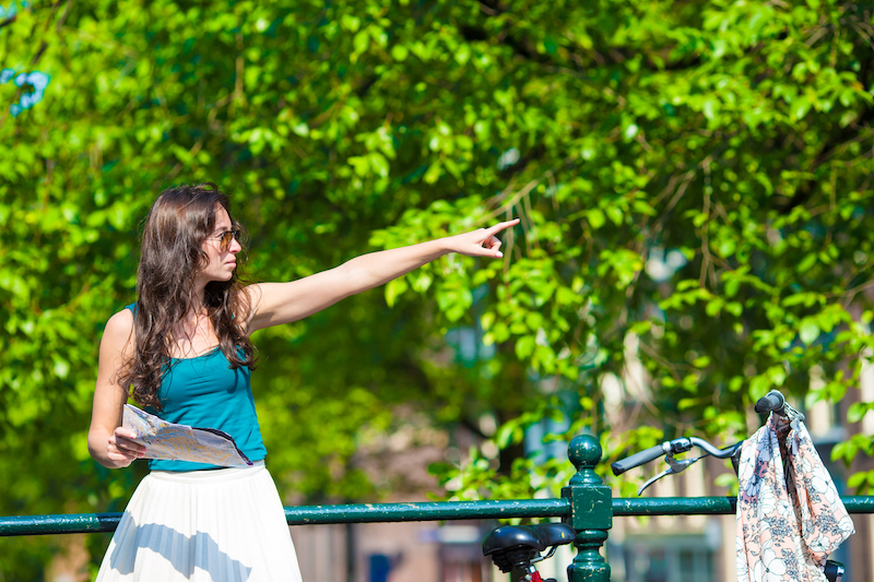 Happy young woman with a city map smiling riding on bicycle