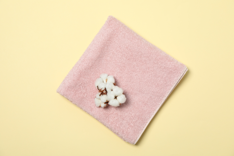 Towel and cotton flower on beige background