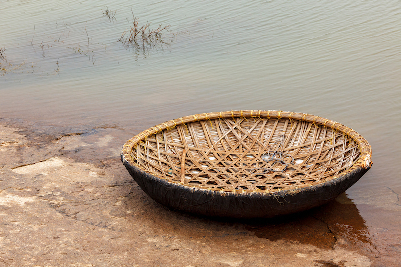 Traditional wickerwork coracle boat in Hampi on bank of Tungabhadra river, Hampi, Karnataka, India