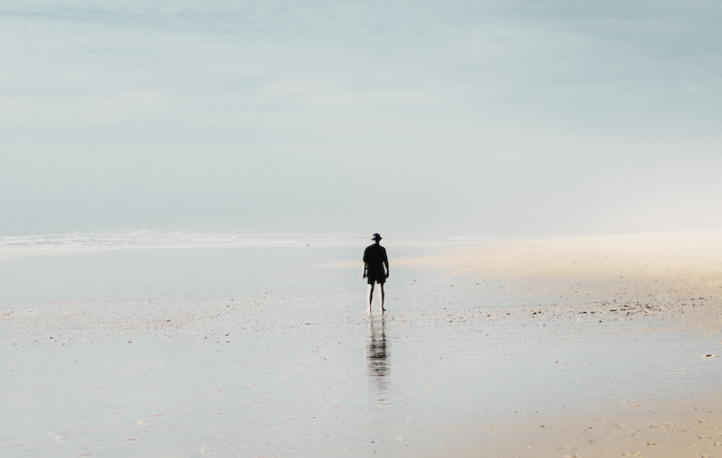 Human on sand beach near water and cloudy sky