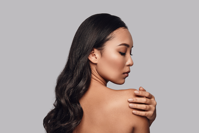 Beautiful young woman touching her shoulder with hand