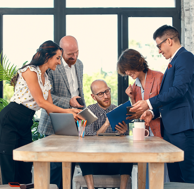 Selective focus of young business man surrounded by colleagues, each proposes a project, asks for approval or signing