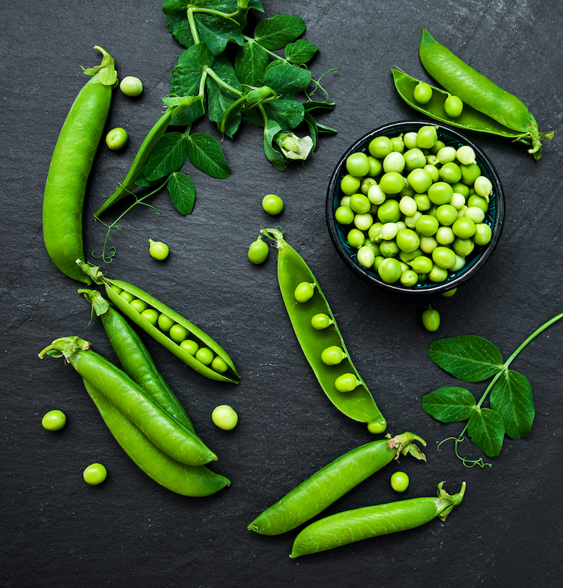 green peas  on a black stone board