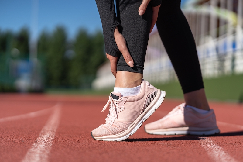 woman holding leg with running shoes on